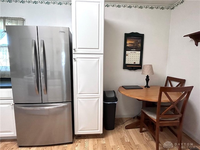 kitchen with light wood finished floors, freestanding refrigerator, and white cabinetry