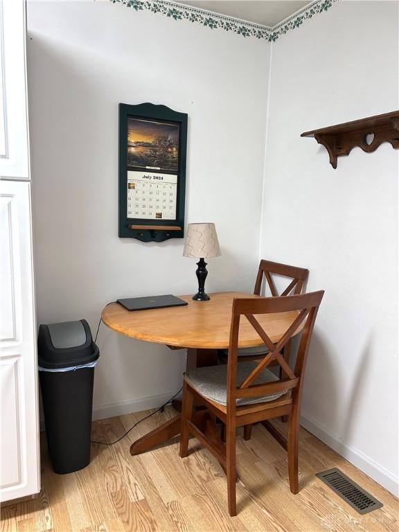 dining area featuring light wood finished floors, baseboards, and visible vents