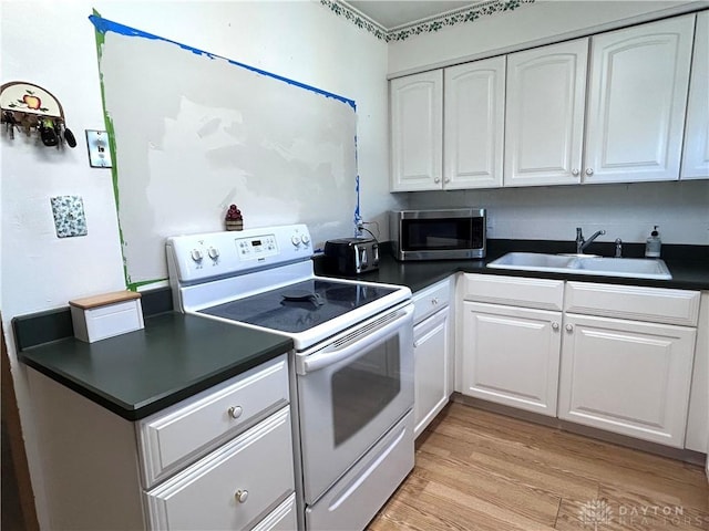 kitchen with dark countertops, stainless steel microwave, white electric range, white cabinetry, and a sink