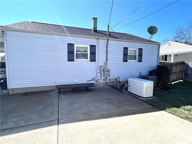 back of house with central AC unit, concrete driveway, a patio, roof with shingles, and fence