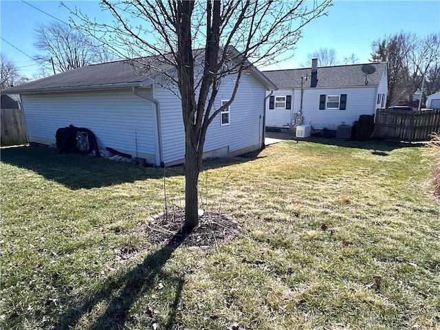 rear view of property featuring a lawn, cooling unit, and fence