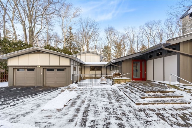 view of snow covered exterior featuring a garage, aphalt driveway, and board and batten siding