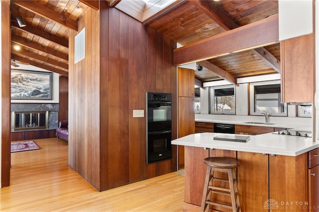 kitchen featuring light wood-style flooring, a sink, wood ceiling, black appliances, and brown cabinetry