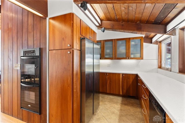 kitchen with brown cabinets, vaulted ceiling with beams, light countertops, appliances with stainless steel finishes, and wood ceiling