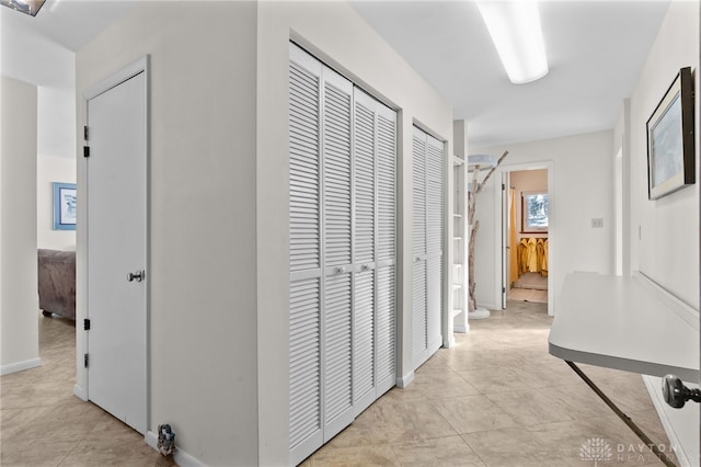 hall featuring baseboards and light tile patterned floors