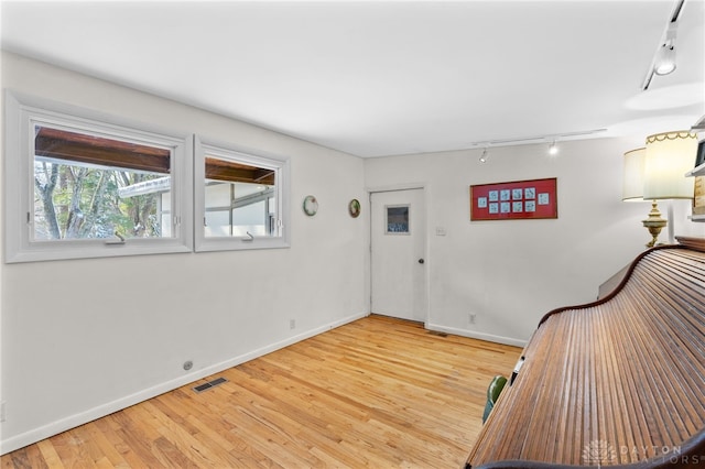 foyer entrance featuring light wood-type flooring, rail lighting, visible vents, and baseboards