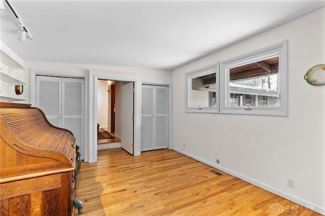 living area featuring light wood-type flooring, visible vents, and baseboards