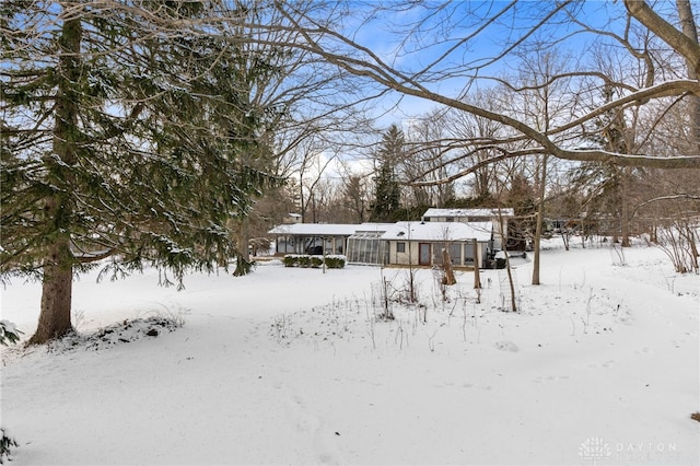 snowy yard featuring a sunroom