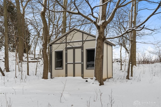 snow covered structure featuring a garage and an outdoor structure