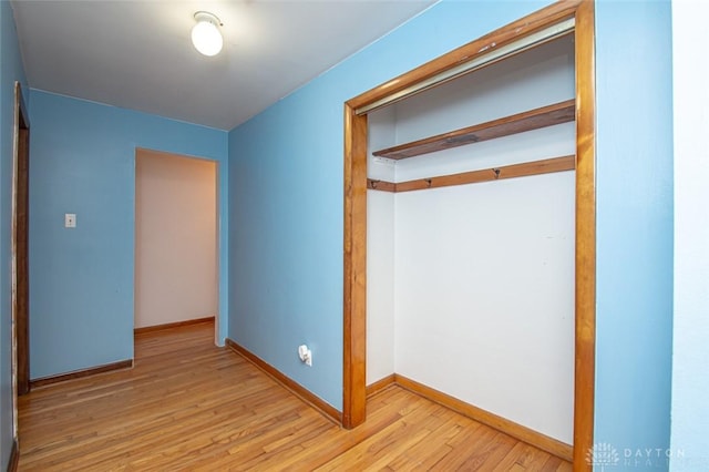 unfurnished bedroom featuring baseboards, a closet, and light wood-style floors