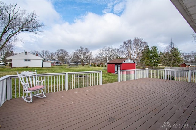 wooden terrace with a storage shed, a lawn, and an outdoor structure