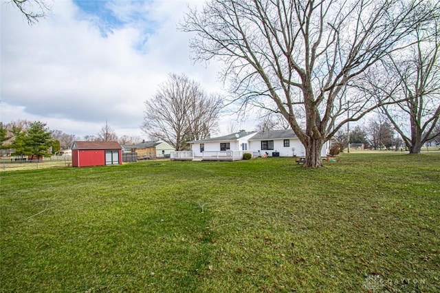 view of yard featuring an outbuilding, fence, a deck, and a storage unit