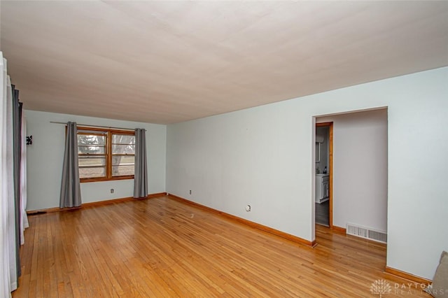 spare room with light wood-type flooring, baseboards, and visible vents