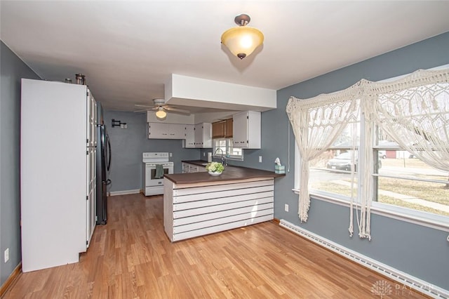 kitchen with light wood finished floors, dark countertops, electric range, baseboard heating, and a peninsula