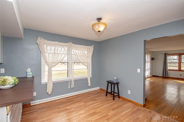 dining space with baseboard heating, wood finished floors, and baseboards