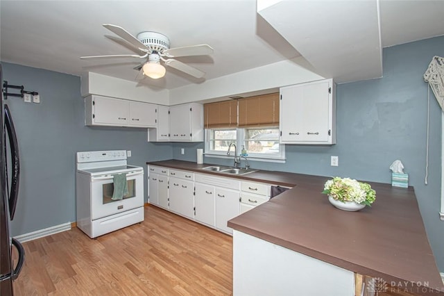 kitchen with electric range, a barn door, dark countertops, light wood-type flooring, and a sink