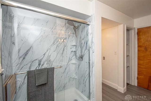 bathroom featuring wood finished floors and a marble finish shower