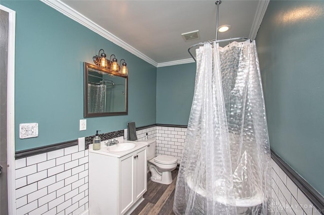 bathroom featuring visible vents, wainscoting, toilet, crown molding, and tile walls