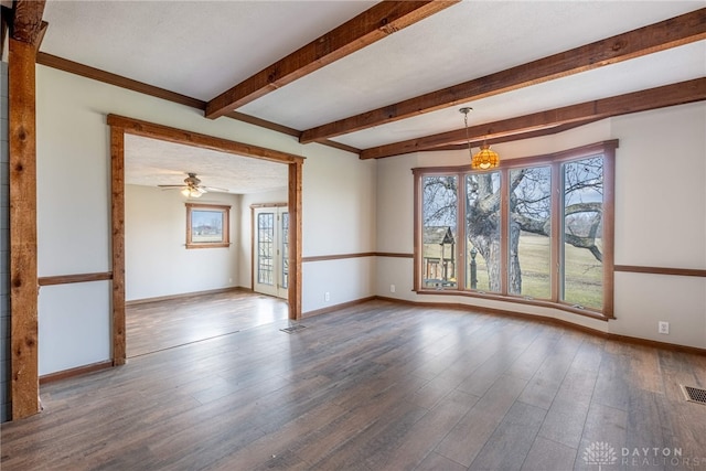 spare room featuring visible vents, wood finished floors, beam ceiling, and baseboards