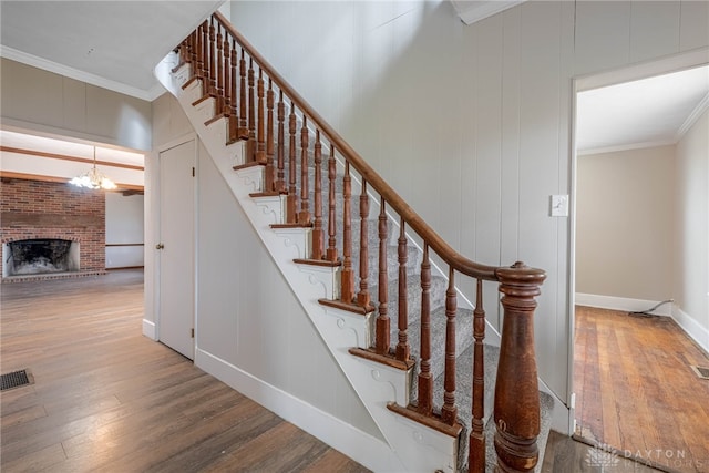 staircase with visible vents, ornamental molding, and wood finished floors