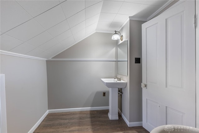 bathroom with crown molding, vaulted ceiling, a sink, wood finished floors, and baseboards