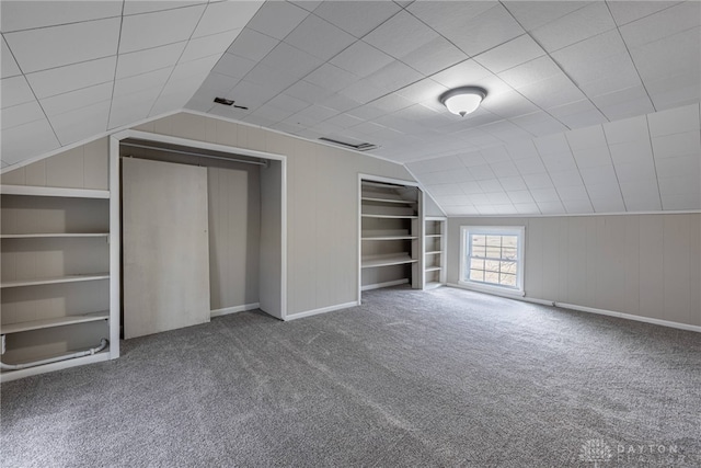 additional living space with built in features, lofted ceiling, visible vents, and carpet