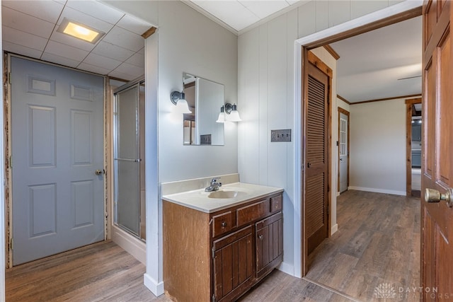 bathroom with wood finished floors, vanity, baseboards, ornamental molding, and a stall shower