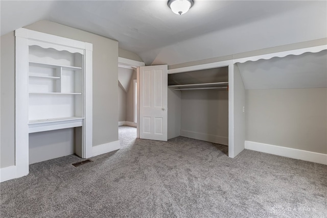 unfurnished bedroom with carpet, a closet, visible vents, and vaulted ceiling