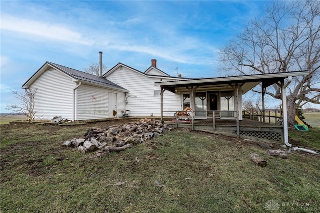 back of house with metal roof and a lawn