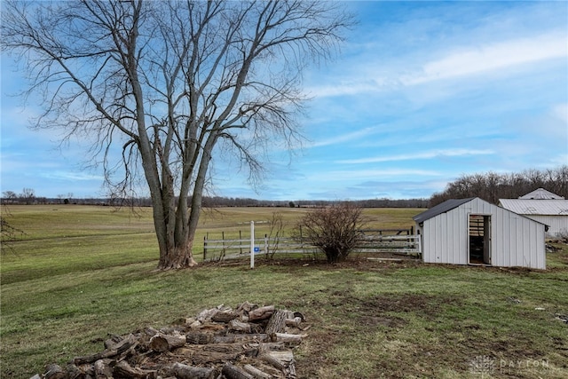 view of yard featuring a pole building, fence, an outbuilding, and a rural view