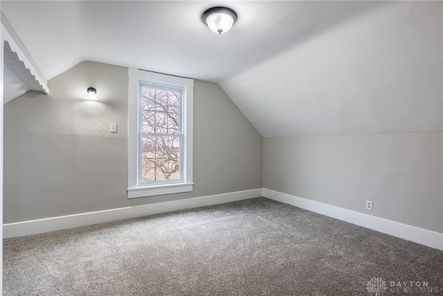 additional living space featuring baseboards, vaulted ceiling, and carpet flooring