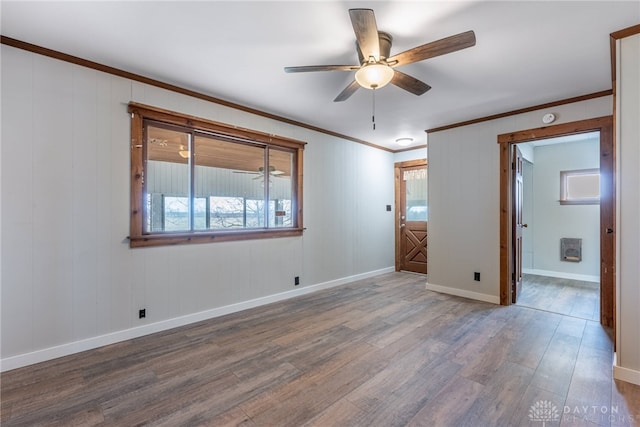 spare room featuring ceiling fan, ornamental molding, wood finished floors, and baseboards