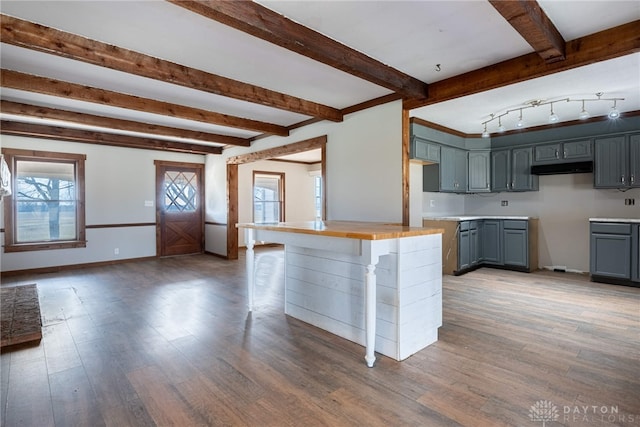 kitchen with baseboards, beamed ceiling, wood finished floors, and gray cabinetry