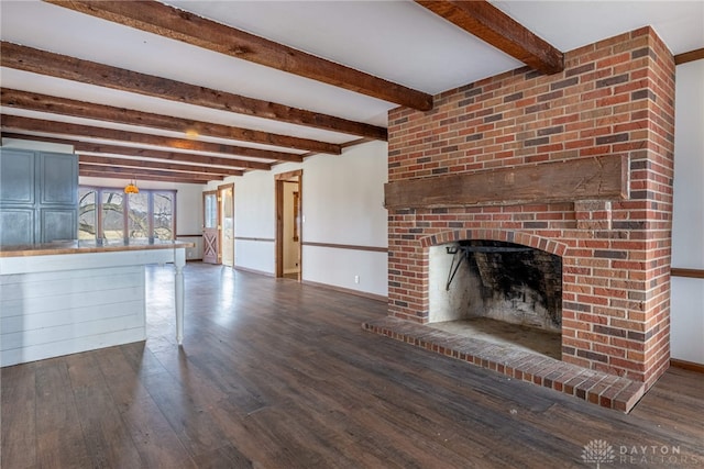 unfurnished living room with a brick fireplace, beam ceiling, baseboards, and dark wood-type flooring