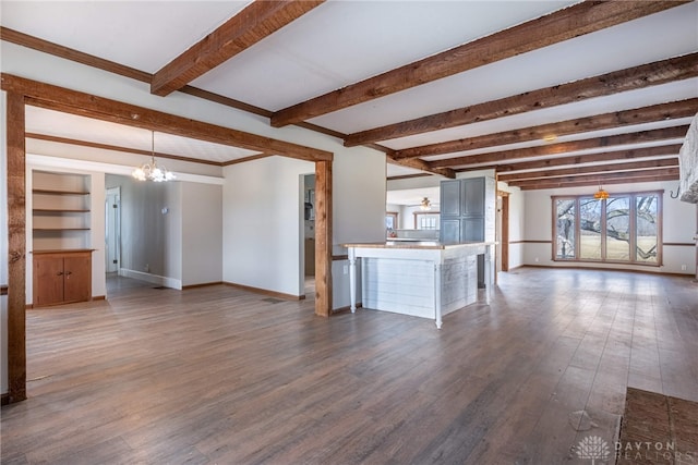 unfurnished living room featuring ceiling fan with notable chandelier, dark wood finished floors, beam ceiling, and baseboards