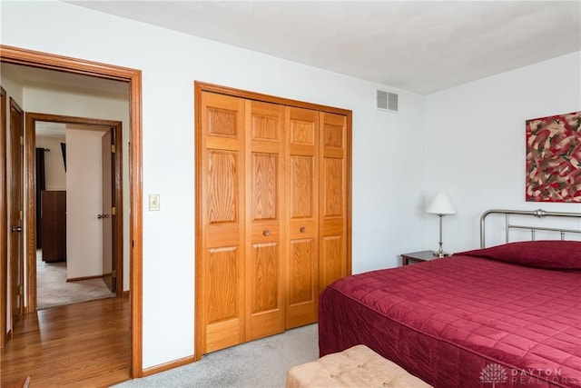 carpeted bedroom with a closet, visible vents, and baseboards