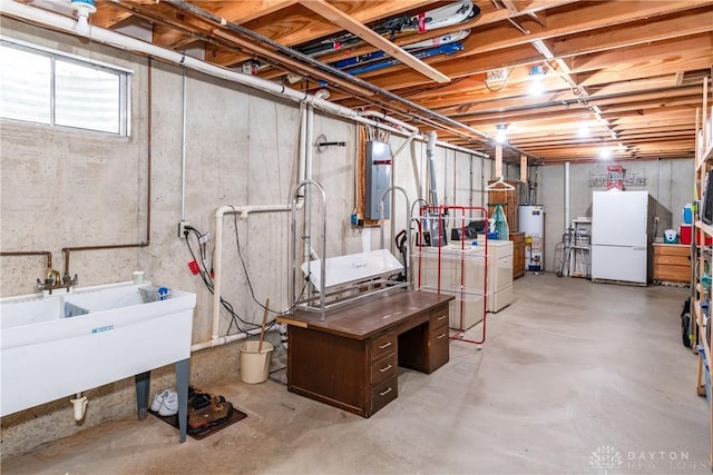 below grade area featuring water heater, a sink, washing machine and dryer, and freestanding refrigerator