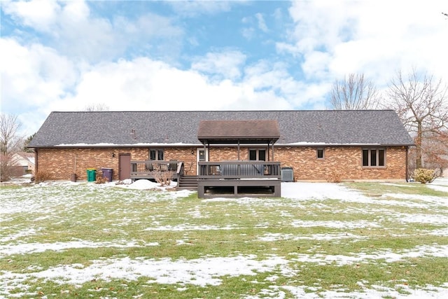 snow covered property featuring a deck and brick siding