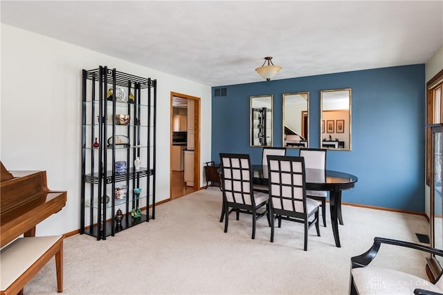 carpeted dining room with visible vents and baseboards