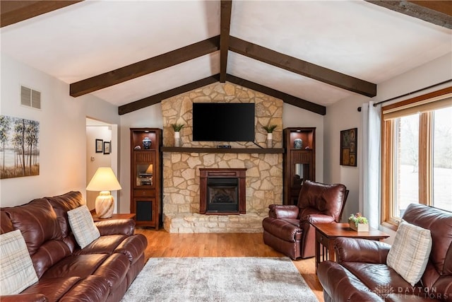 living room with visible vents, a fireplace, lofted ceiling with beams, and wood finished floors