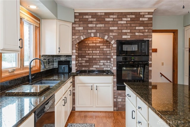 kitchen featuring tasteful backsplash, white cabinets, a sink, light wood-type flooring, and black appliances