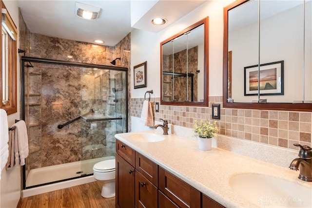 full bathroom featuring a stall shower, a sink, toilet, and double vanity