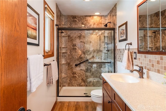 bathroom featuring a stall shower, vanity, toilet, and wood finished floors