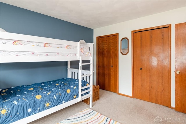 bedroom with baseboards, carpet floors, and multiple closets