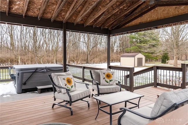 deck featuring a hot tub, an outbuilding, and a shed