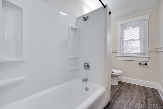 full bath featuring baseboards, tub / shower combination, toilet, and wood finished floors