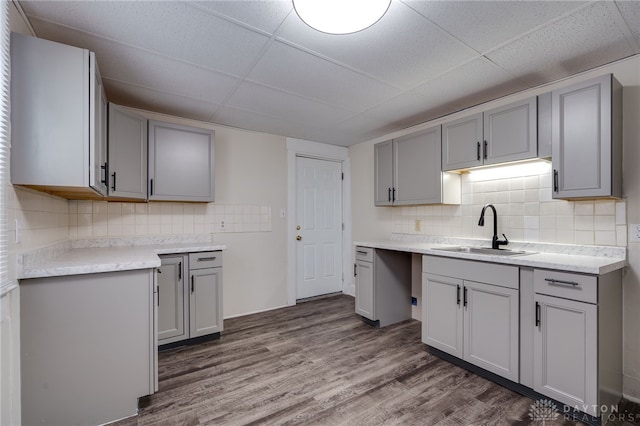 kitchen featuring a drop ceiling, a sink, dark wood finished floors, and gray cabinetry