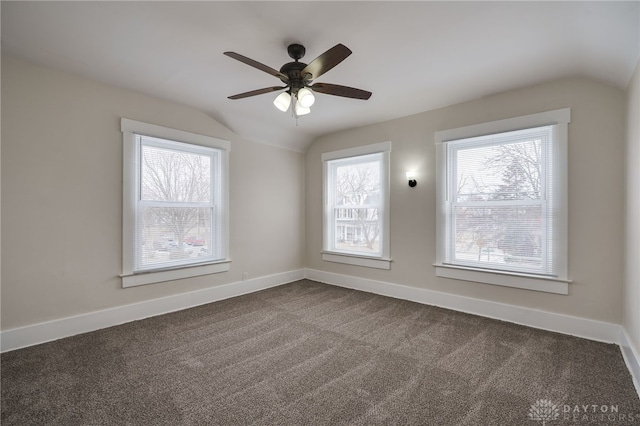 spare room with dark carpet, baseboards, vaulted ceiling, and a ceiling fan