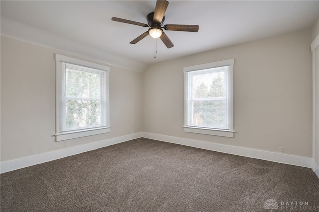 empty room featuring dark colored carpet, plenty of natural light, and baseboards