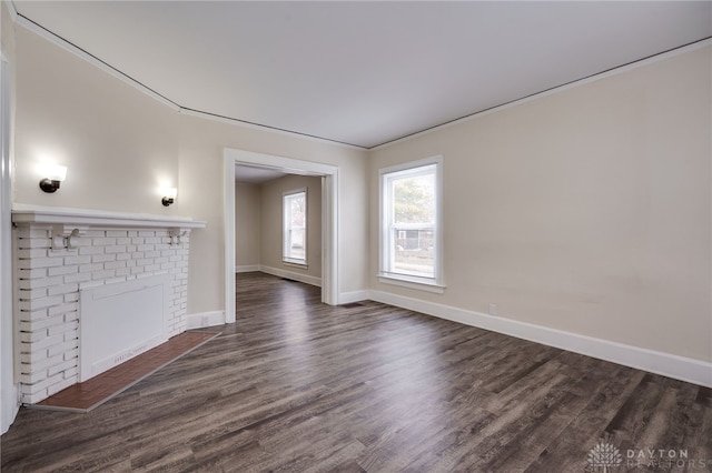 unfurnished living room featuring dark wood-type flooring, crown molding, a fireplace, and baseboards